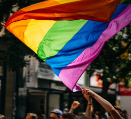 Group of people in the street with a rainbow LGBTQ flag being waved in the air