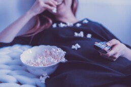Person watching tv and eating popcorn