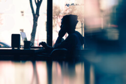 Person remote working in public space in dark shadow